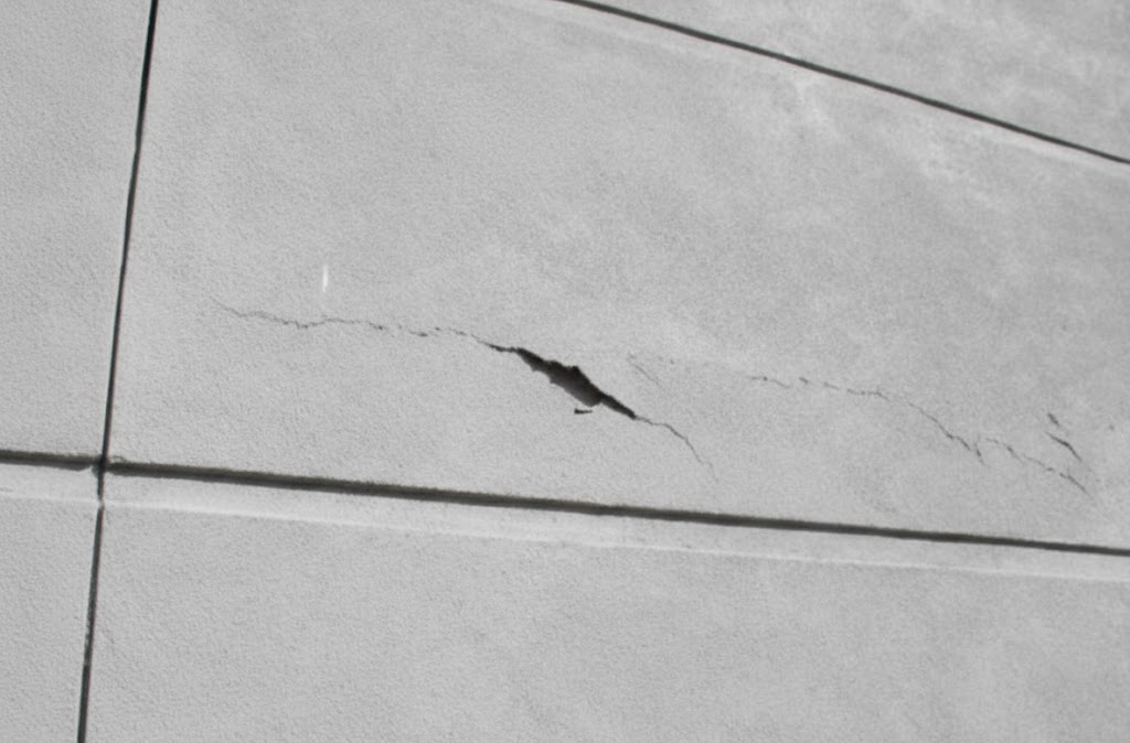 A building facade displaying visible structural cracking on a concrete post tension slab.